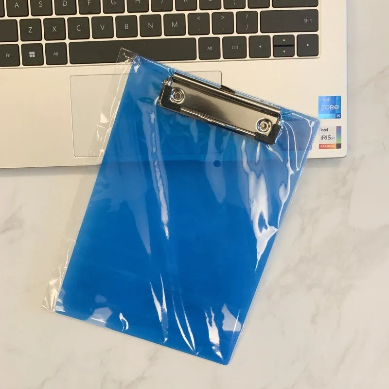 A4 transparent plastic writing board pad with metal clip in blue colour on a desk