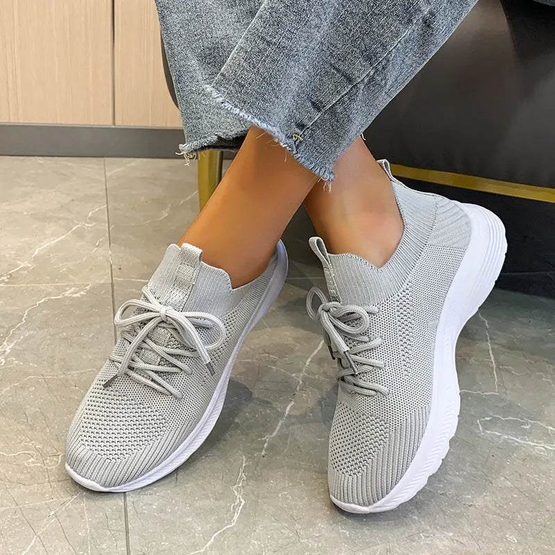 Women's low-top running shoes with mesh lining and Flyknit upper in creamy white, grey, or orange colours
