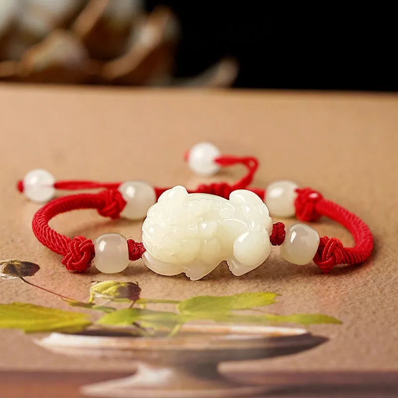 A Hetian jade bracelet with braided black and red rope in a Chinese style design.