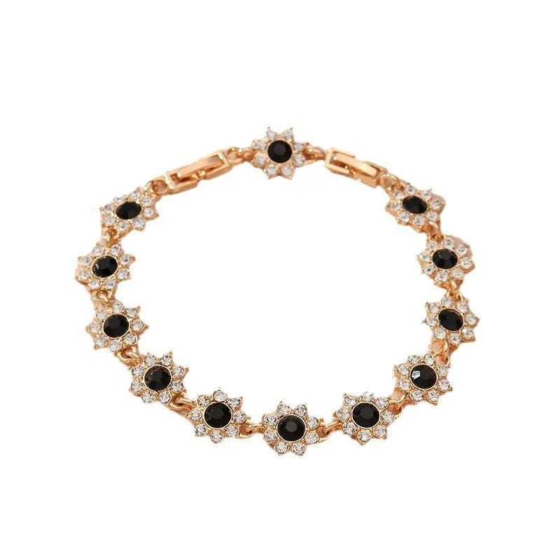 A gold or silver electroplated zinc alloy flower bracelet with coloured gems.