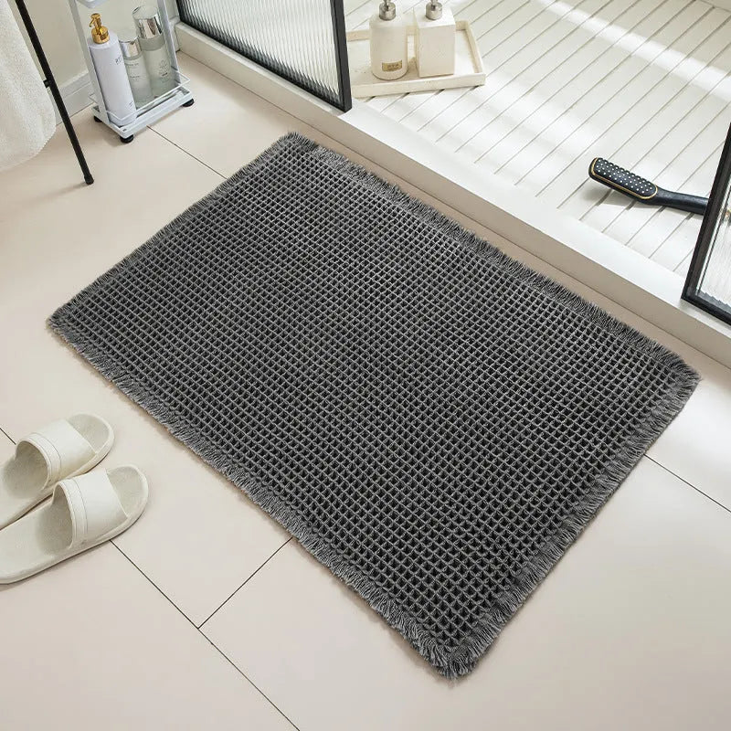 Square checkered-pattern non-slip bathroom carpet in a neutral colour on tiled floor.