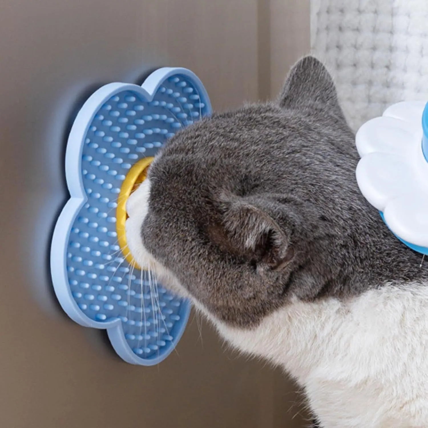 Flower-shaped blue silicone dog licking mat with suction cups on a smooth tile surface.