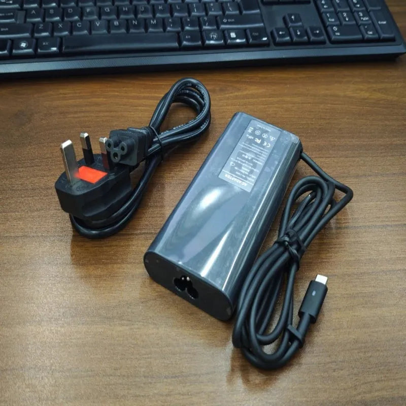 Black 65W Type-C laptop power adapter with multiple international power cords for UK US EU AU and ZA plugs.