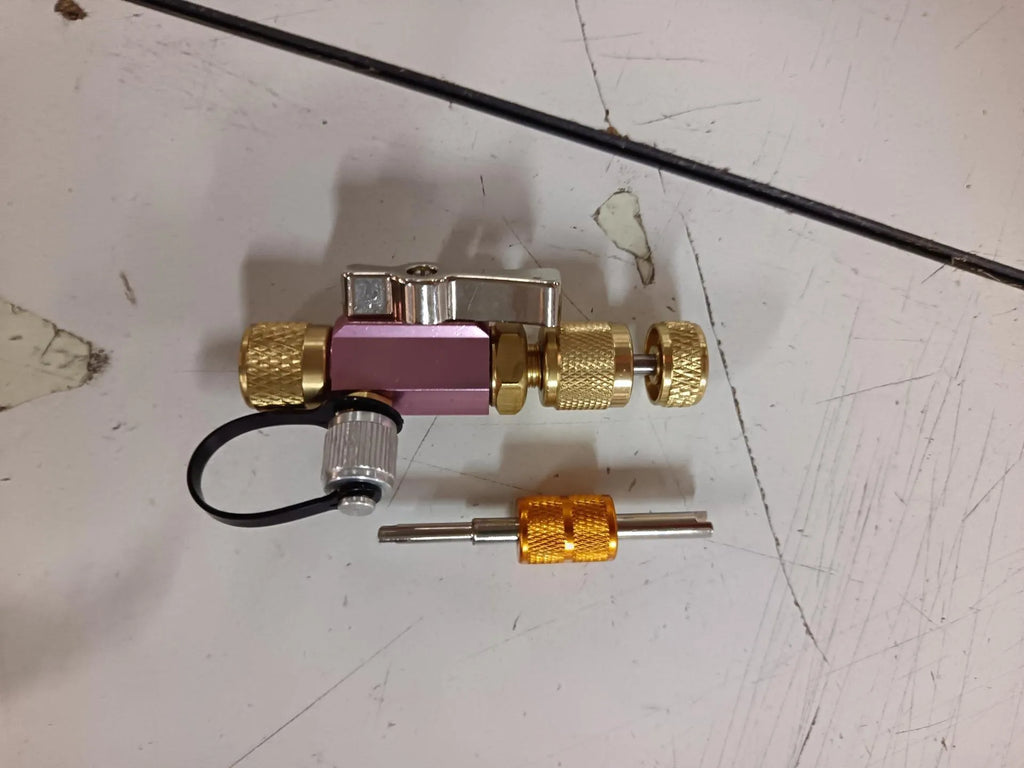 Metal valve core disassembly tool set showing black and pink valve removers and a valve core wrench.