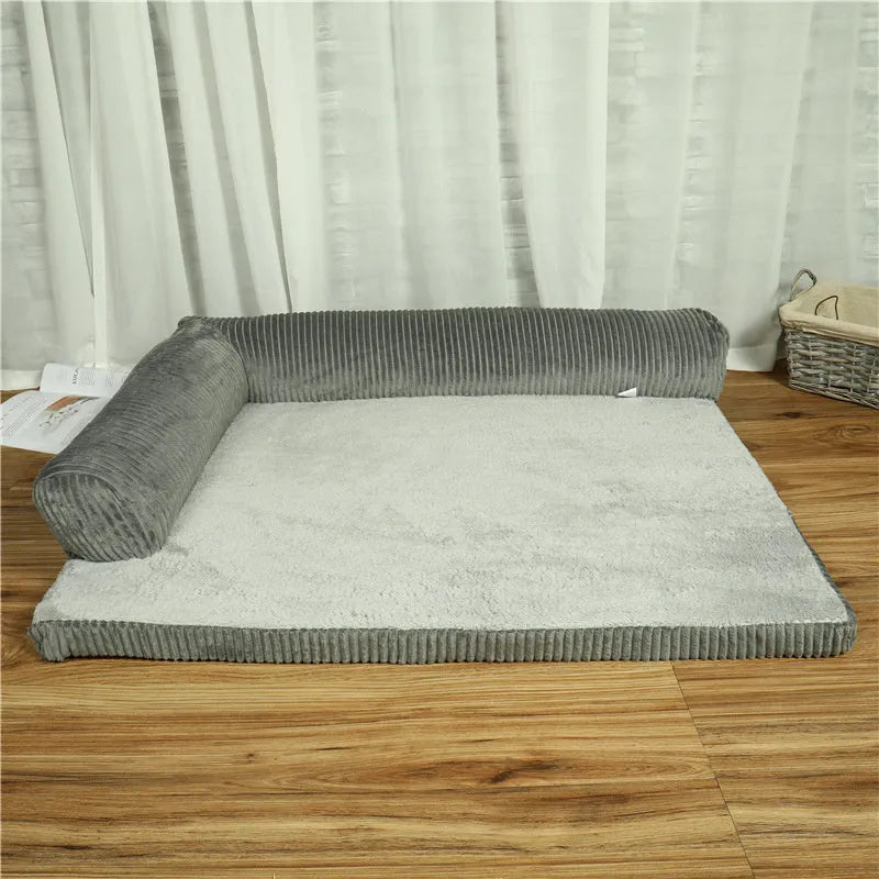 A corduroy pet sofa dog bed with a raised bolster, shown in a grey colour on a wooden floor.