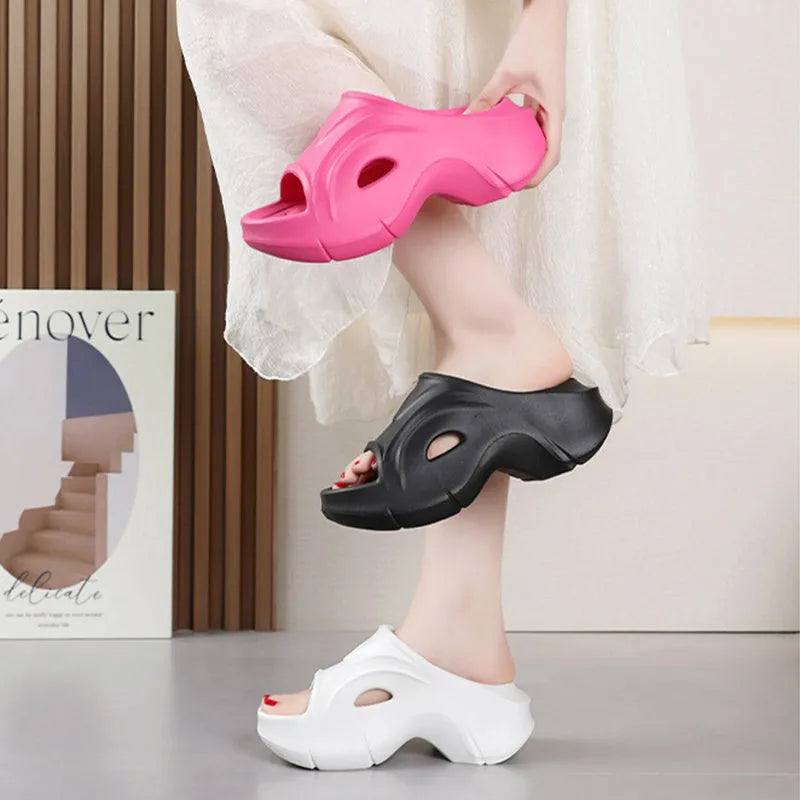 Women's white EVA slippers with a thick sole and round toe on a sandy beach.