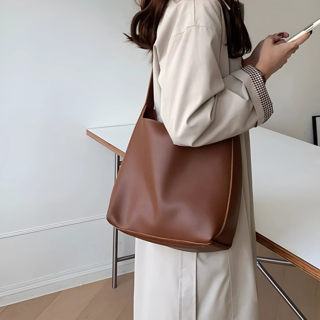 Two women's soft PU shoulder bags with swing threads, one black and one brown, showing structured design.