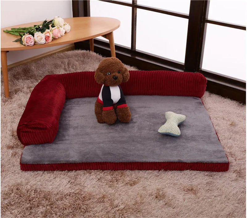 A corduroy pet sofa dog bed with a raised bolster, shown in a grey colour on a wooden floor.