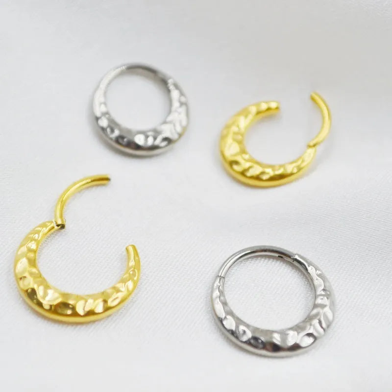 Close-up of a titanium alloy concave-convex nose ring in gold finish, showing carved detail and ring shape.