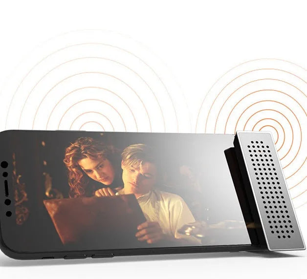 A portable black ABS plastic phone amplifier holder on a desktop, showing a mobile phone inserted for sound amplification.