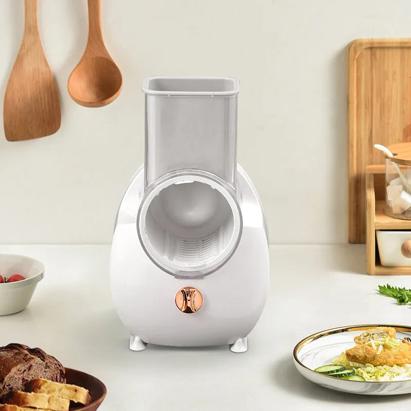 White electric vegetable slicer with rotary grater, feeding port, and strong suction base on a kitchen counter.