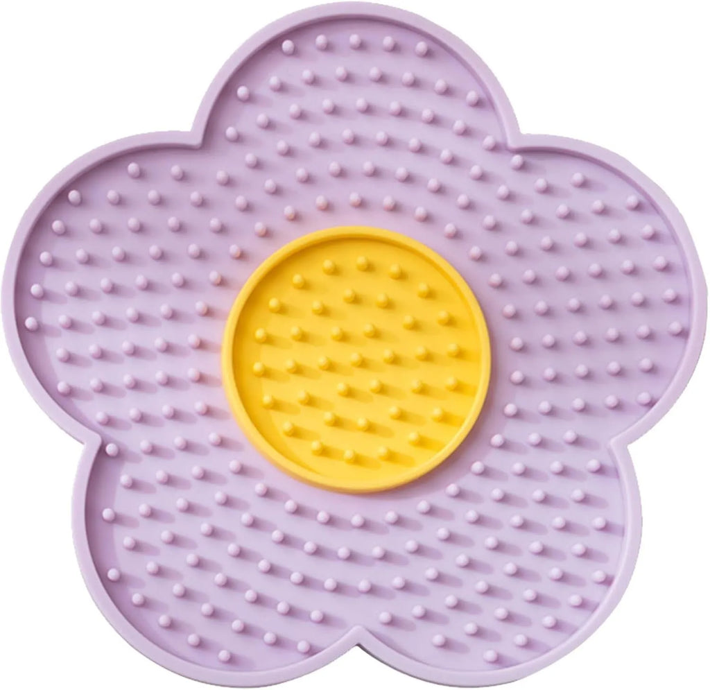 Flower-shaped blue silicone dog licking mat with suction cups on a smooth tile surface.