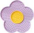 Flower-shaped blue silicone dog licking mat with suction cups on a smooth tile surface.
