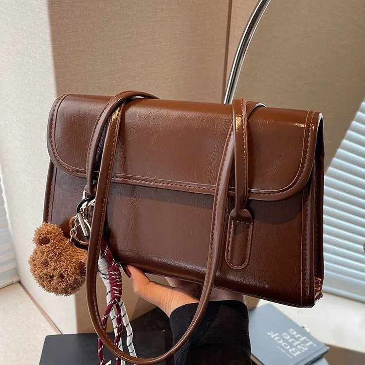 Brown women's PU leather shoulder bag with square shape, pendant detail, and double shoulder straps