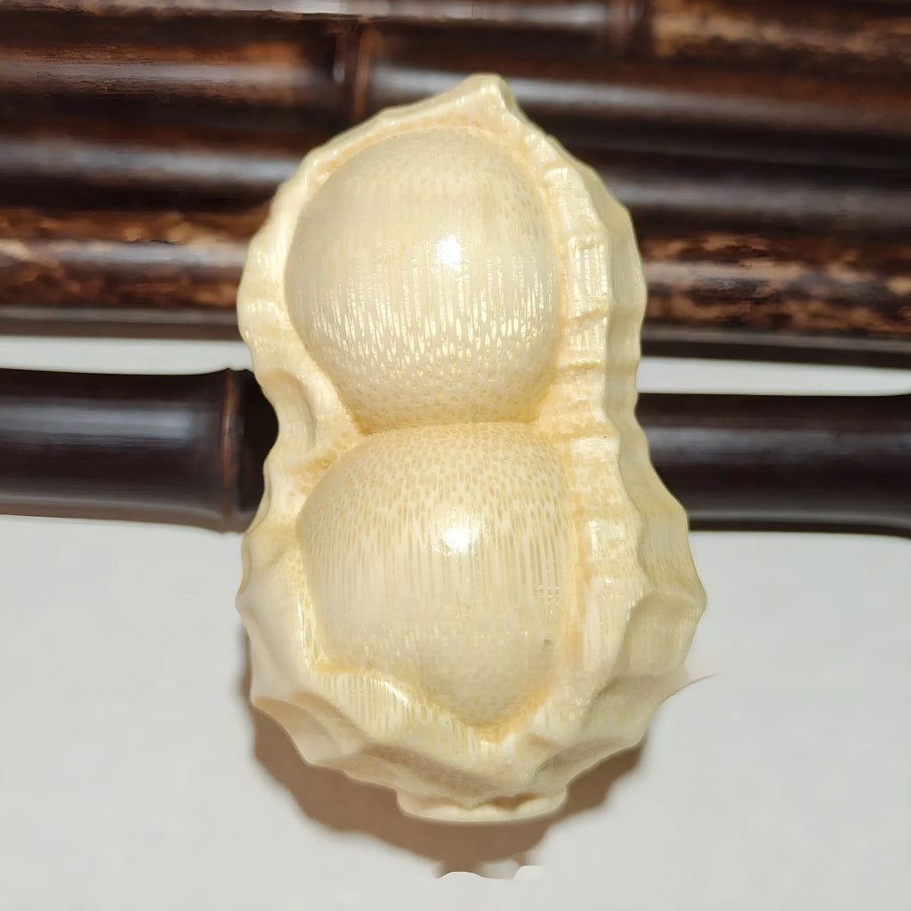 Solid natural bamboo hand-carved peanut ornament on a plain background.
