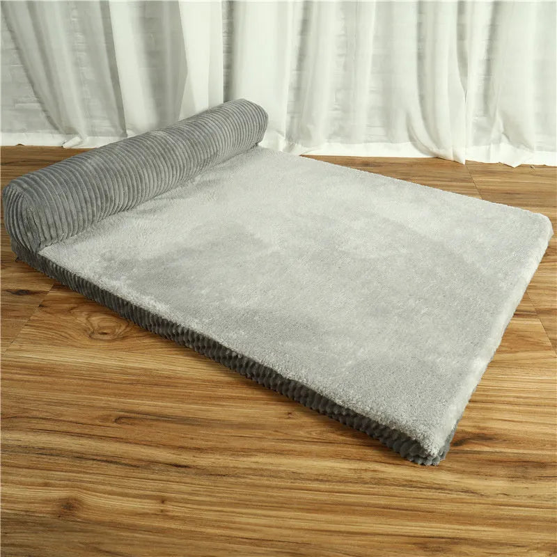 A corduroy pet sofa dog bed with a raised bolster, shown in a grey colour on a wooden floor.