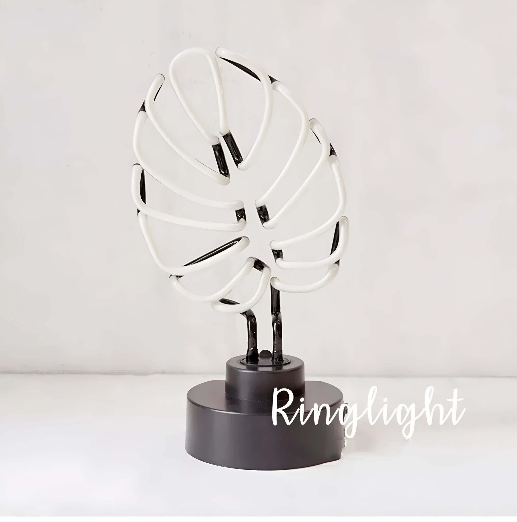 White bamboo-shaped desktop lamp with green light tube on a wooden desk.