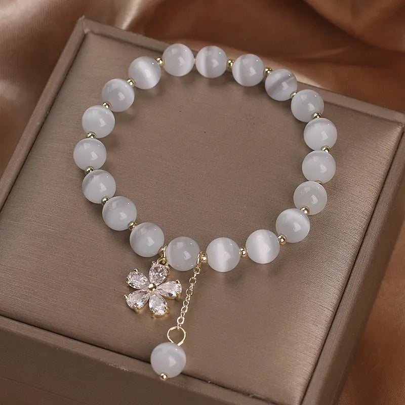 White cat's eye stone flower bracelet with silver-tone details and a hanging tassel charm.