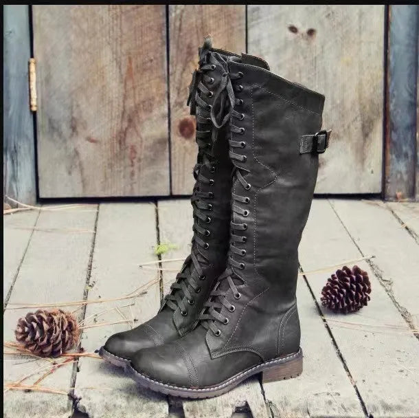 Black chunky heel high leg boots with a round toe and short stout heel on a plain background.