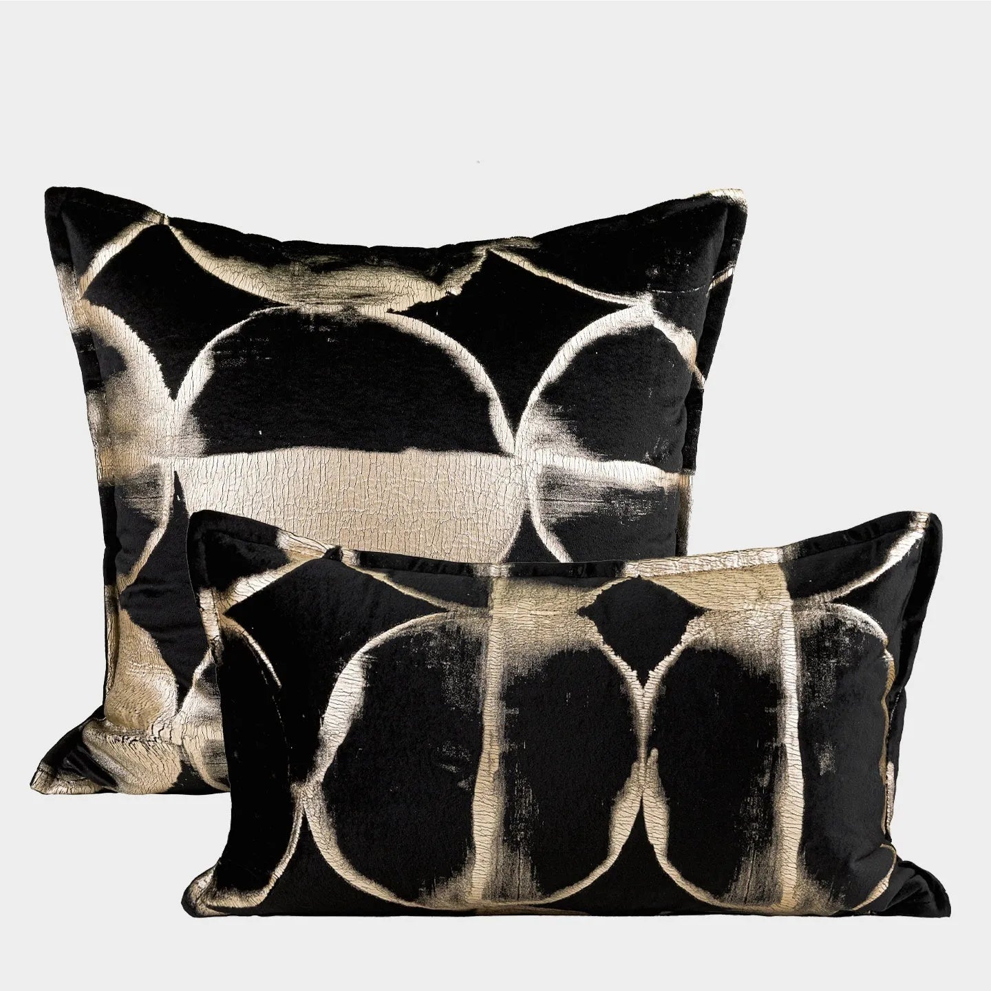 Black and gold abstract patterned flannel decorative pillow with removable cover on a grey sofa.