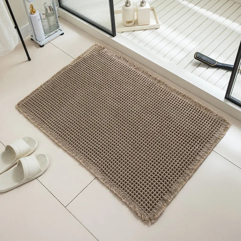 Square checkered-pattern non-slip bathroom carpet in a neutral colour on tiled floor.