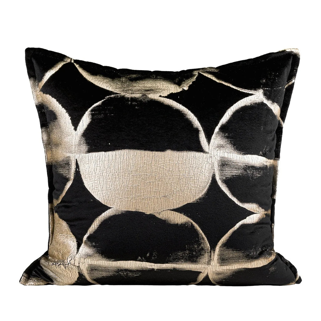 Black and gold abstract patterned flannel decorative pillow with removable cover on a grey sofa.