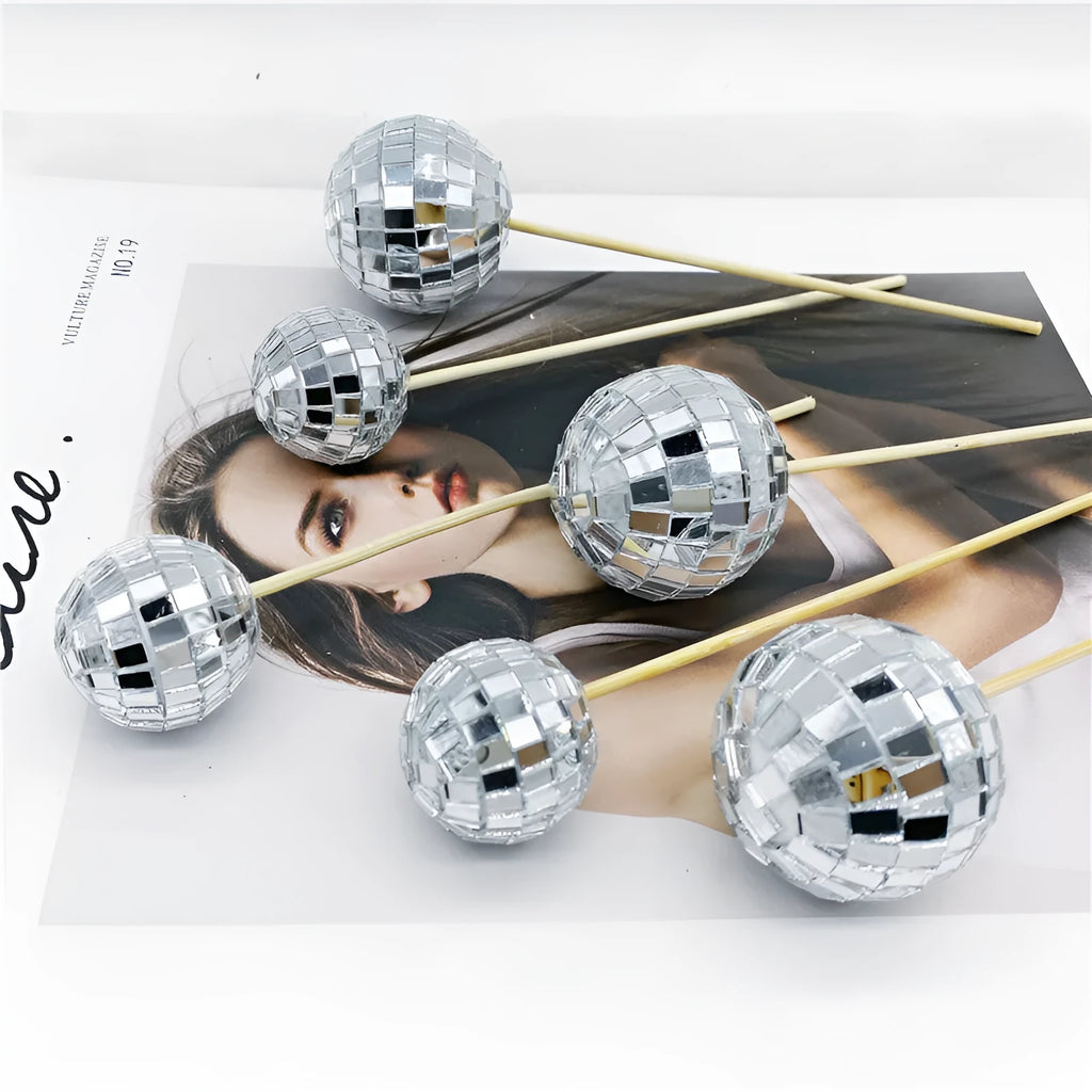 Silver reflective glass disco ball cake topper on a wooden stick for birthday party decoration.