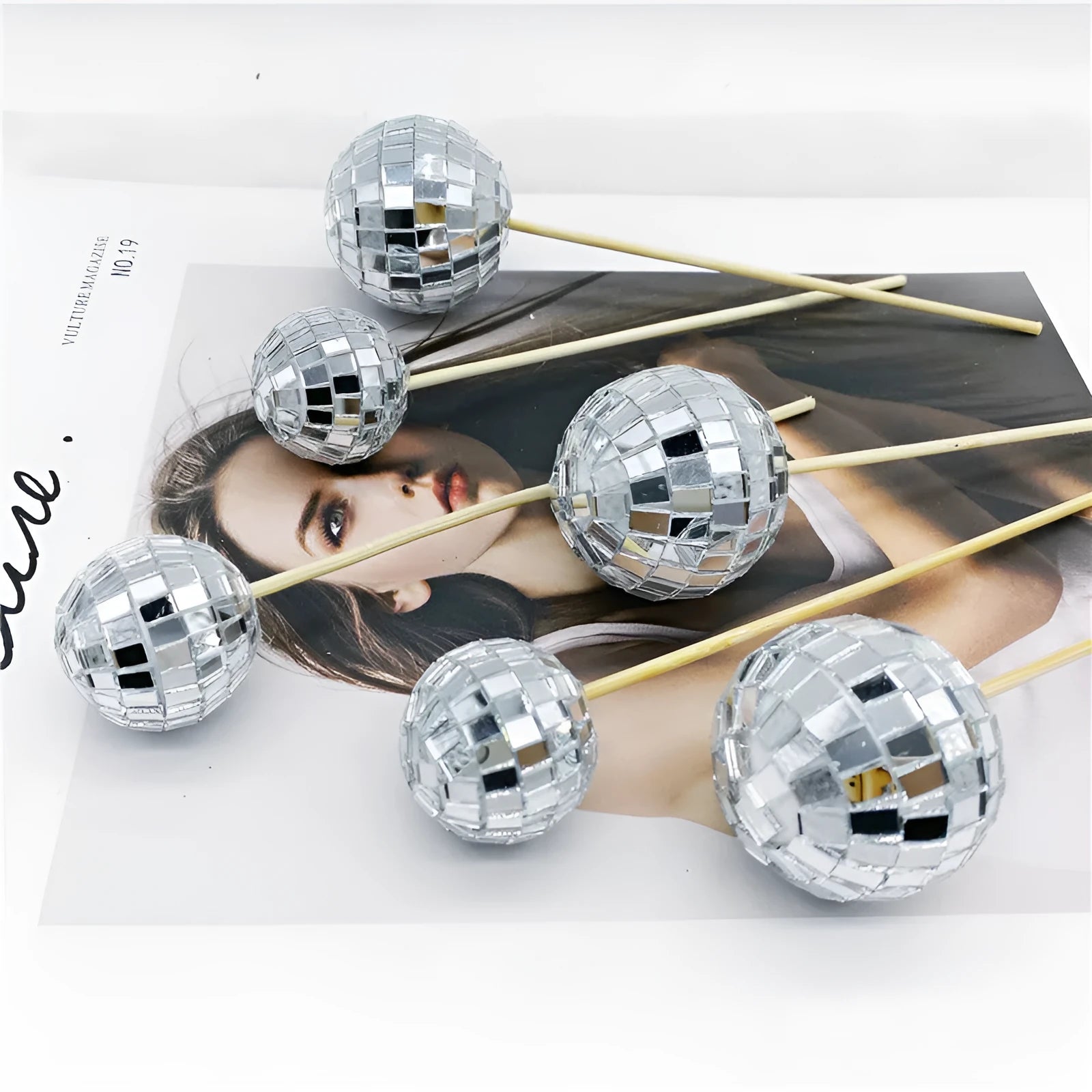Silver reflective glass disco ball cake topper on a wooden stick for birthday party decoration.