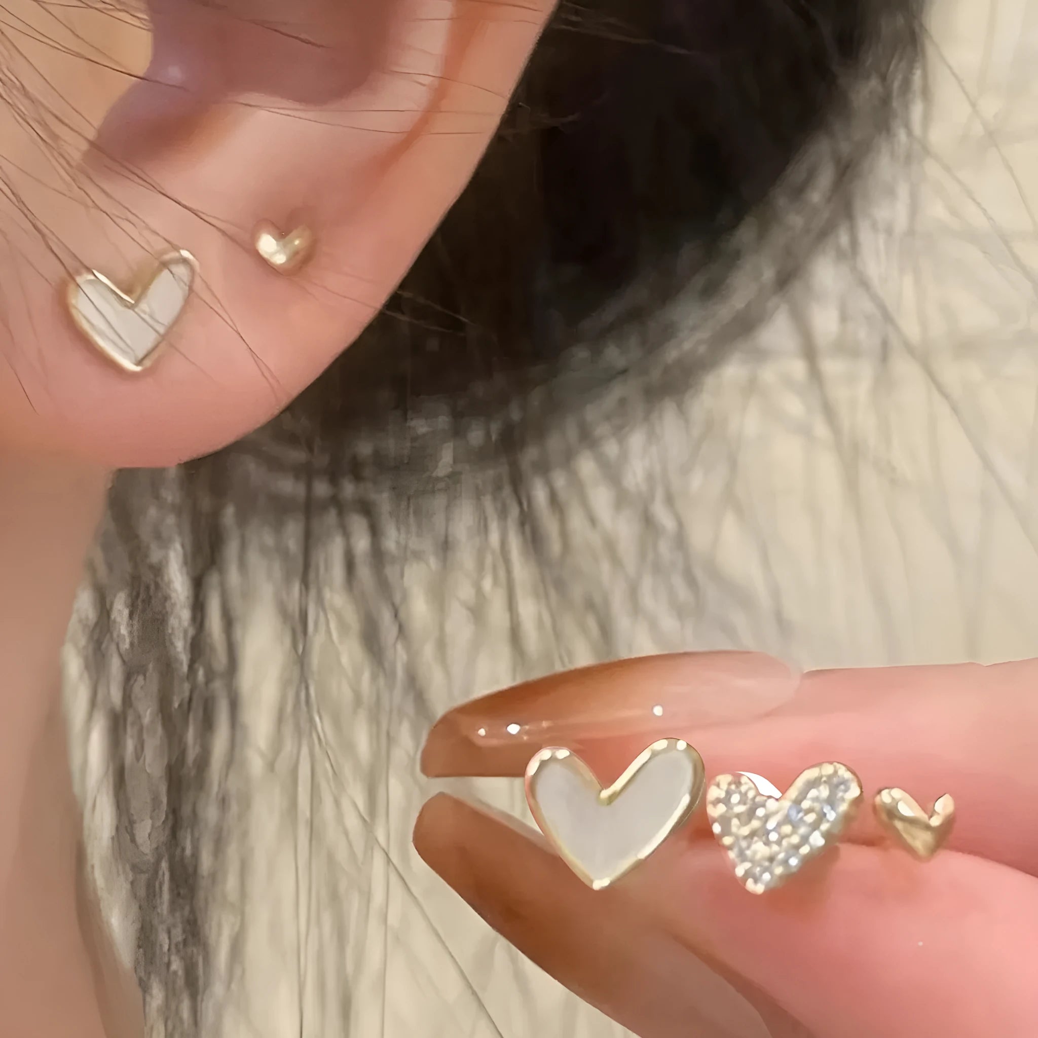 Three pairs of heart-shaped electroplated alloy earrings in gold, black, black and white, and pink colour finishes