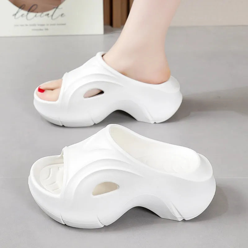 Women's white EVA slippers with a thick sole and round toe on a sandy beach.