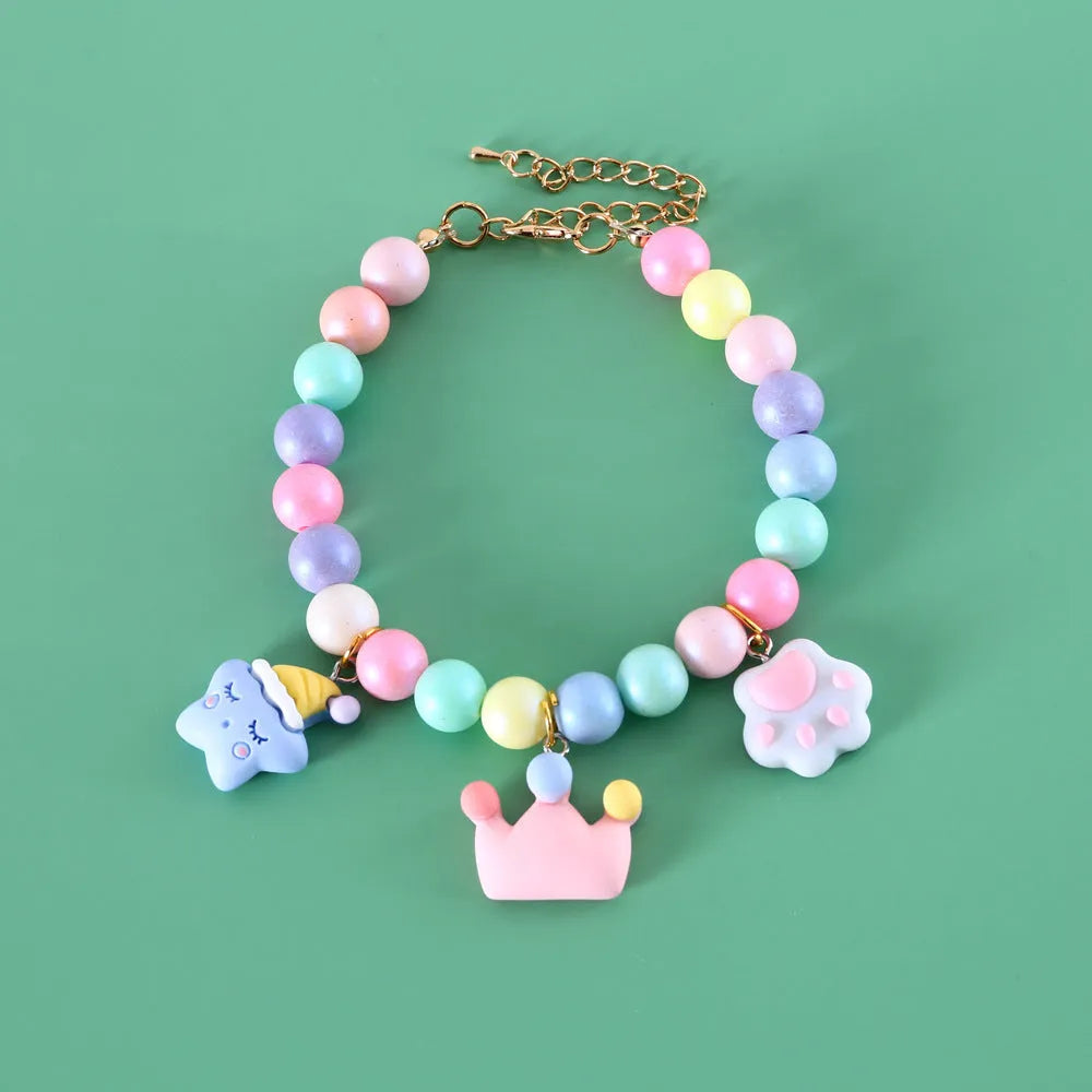 Macaron-coloured resin pet collar and bracelet set for birthday photoshoots on a neutral background.
