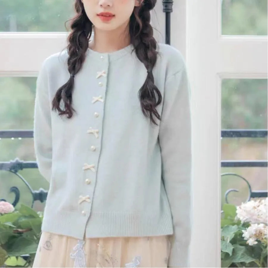 Women's solid colour cardigan sweater with pearl buttons in a light blue shade, shown open.