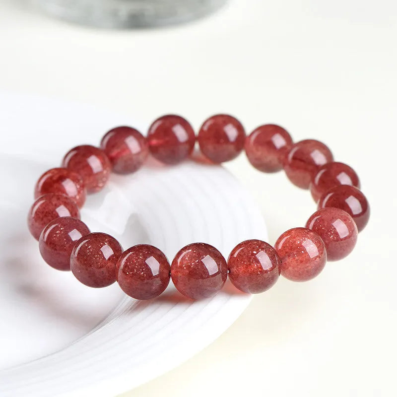 Natural cherry red strawberry quartz bracelet with geometry-shaped beads on a white background.