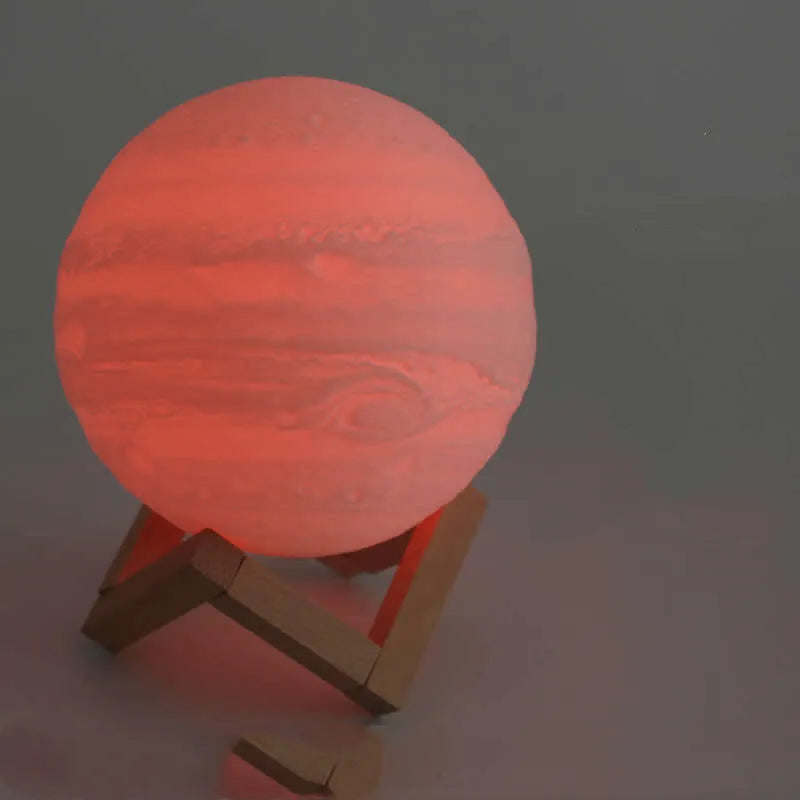 3D printed moon lamp glowing on a wood stand, showing detailed crater texture.