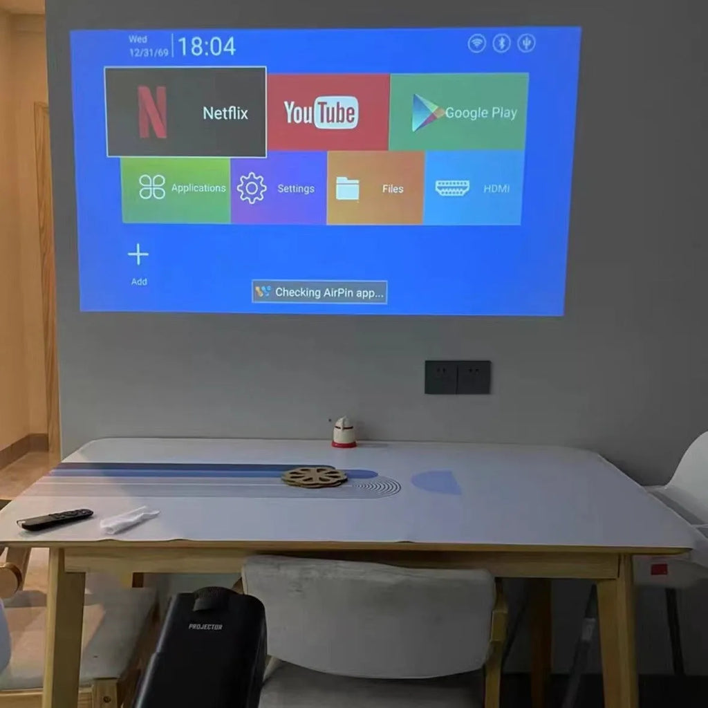 A white HD wireless game projector for home use on a wooden surface.