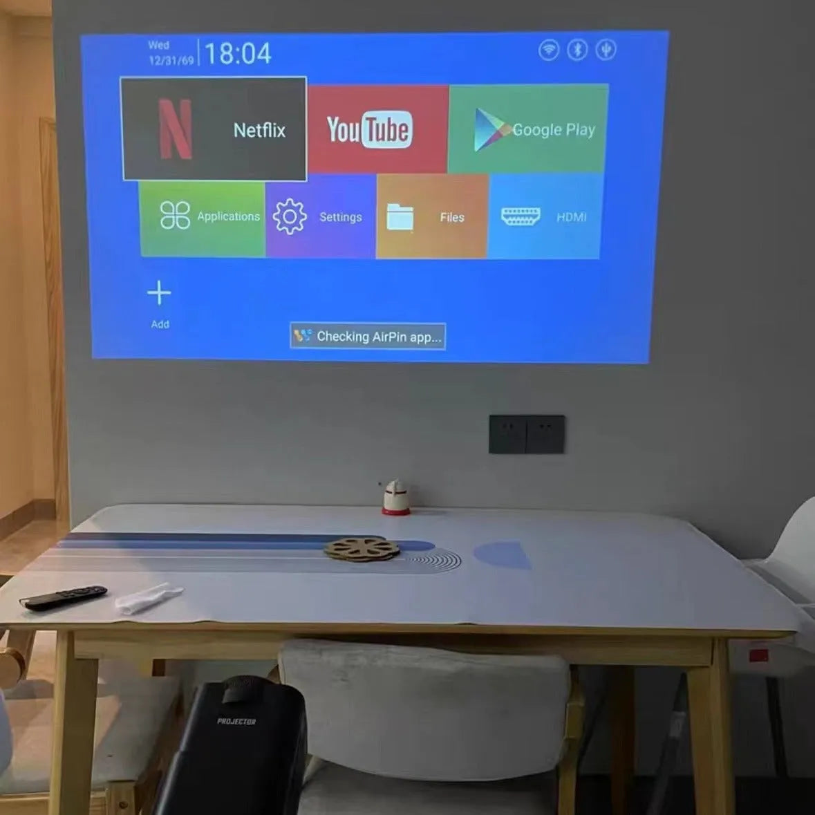 A white HD wireless game projector for home use on a wooden surface.