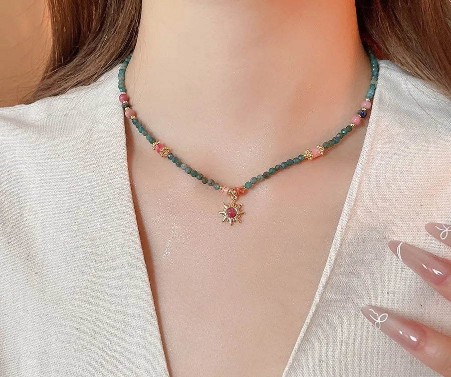 Close-up of a freshwater pearl and geometric stone sun necklace on an adjustable clavicle chain.