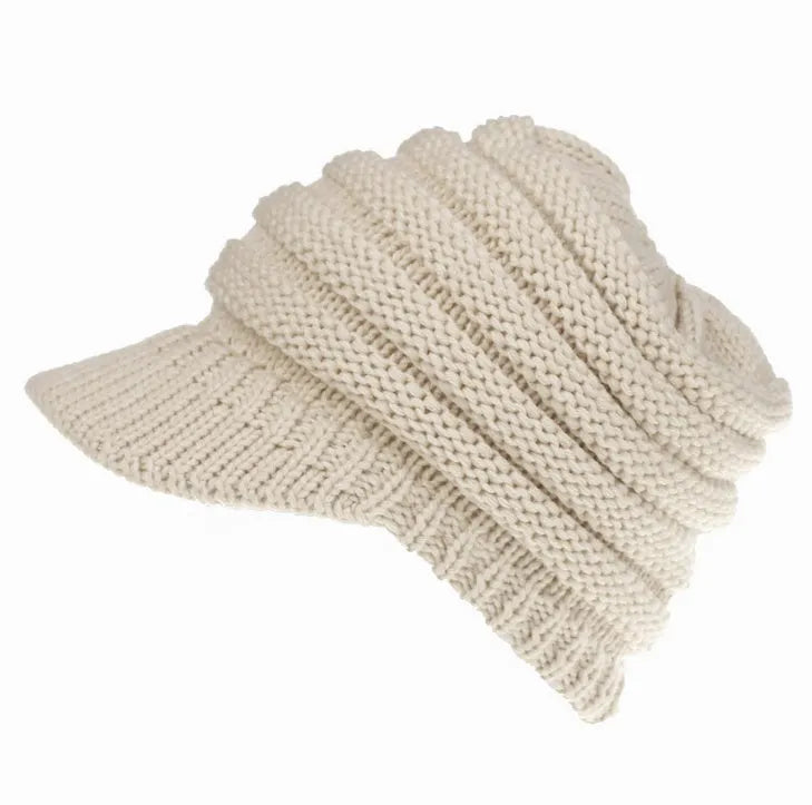 Woman wearing a soft knitted beanie with a ponytail pulled through the hole at the back.