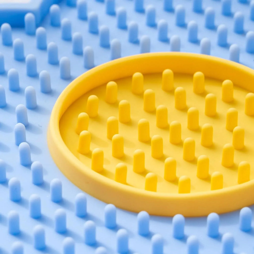 Flower-shaped blue silicone dog licking mat with suction cups on a smooth tile surface.