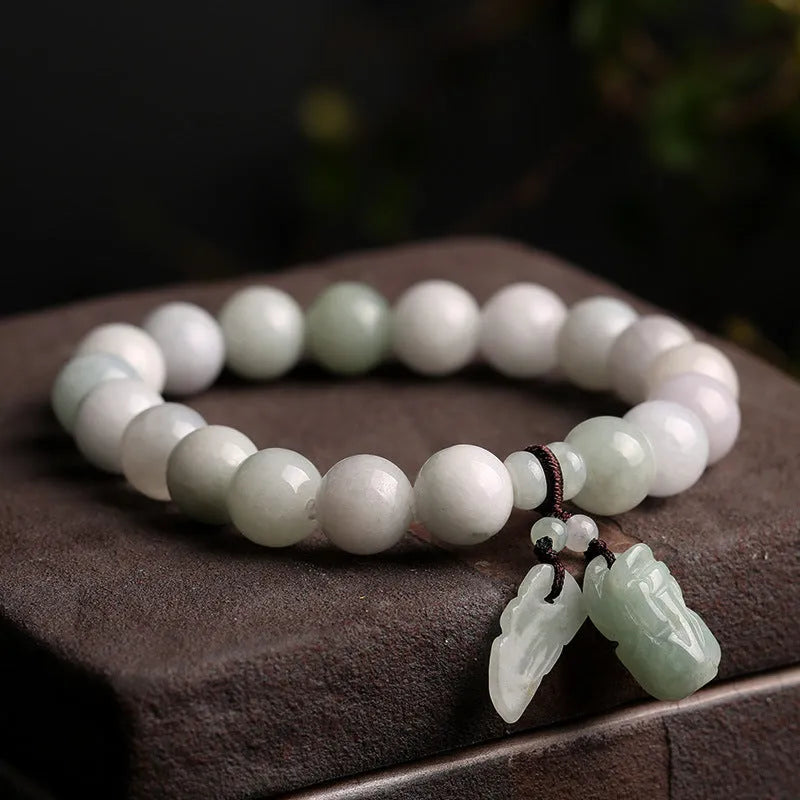 Natural green jade bracelet with a geometric pendant charm on a wrist.