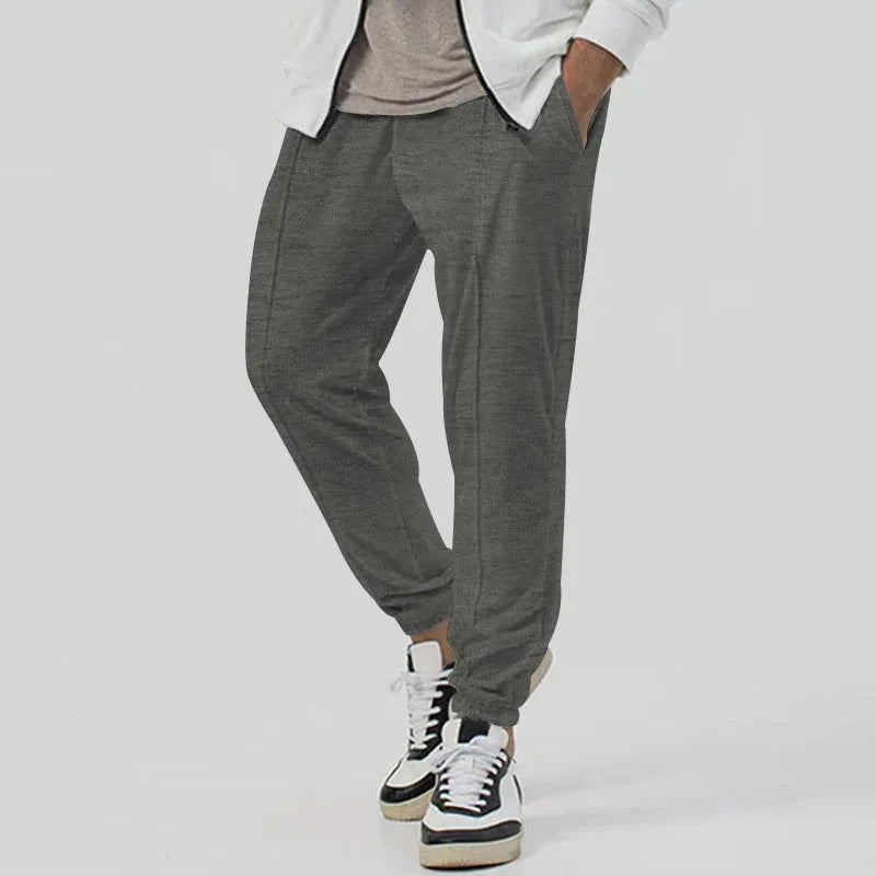 Men's grey casual track sweatpants with loose tapered cut and straight leg design, elastic waistband