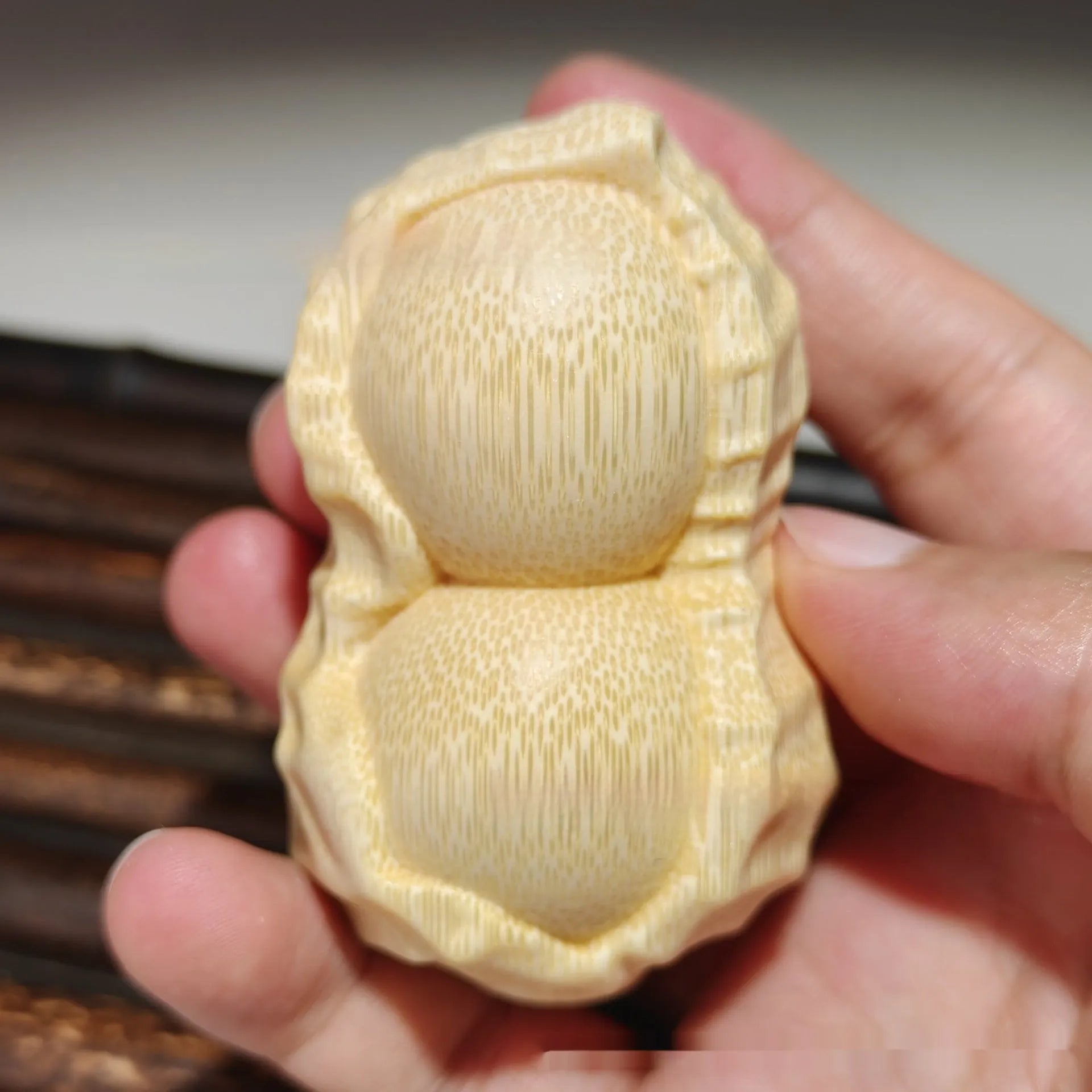 Solid natural bamboo hand-carved peanut ornament on a plain background.