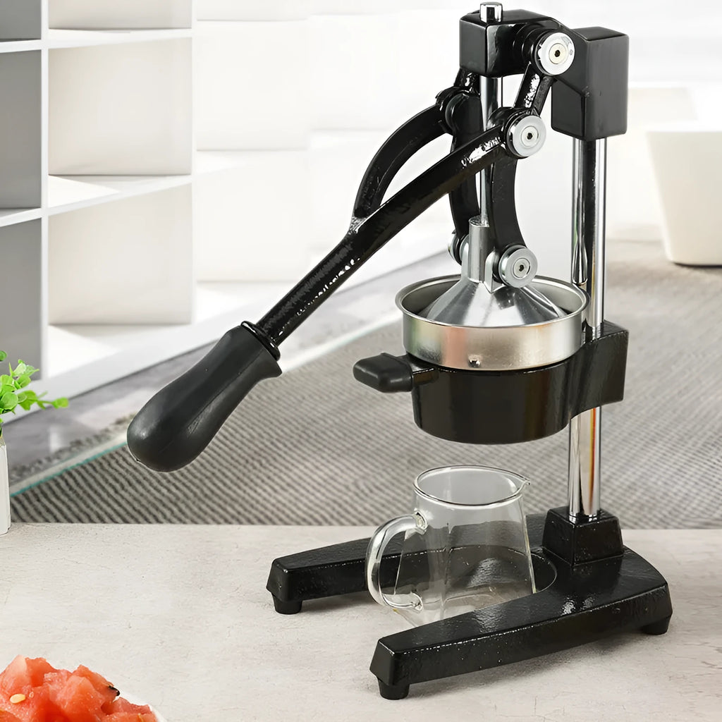 Black cast iron manual juicer with stainless steel strainer on a kitchen counter