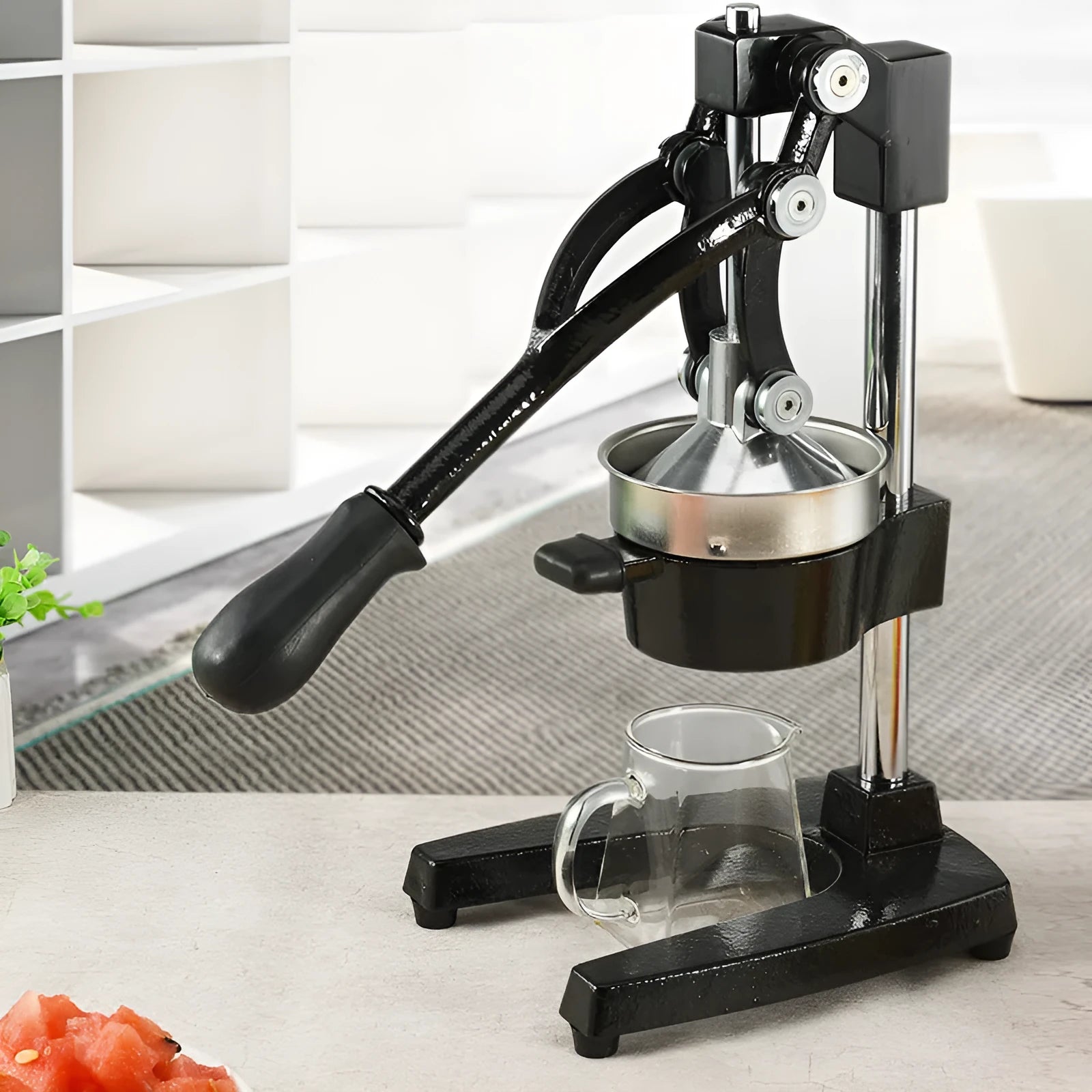 Black cast iron manual juicer with stainless steel strainer on a kitchen counter