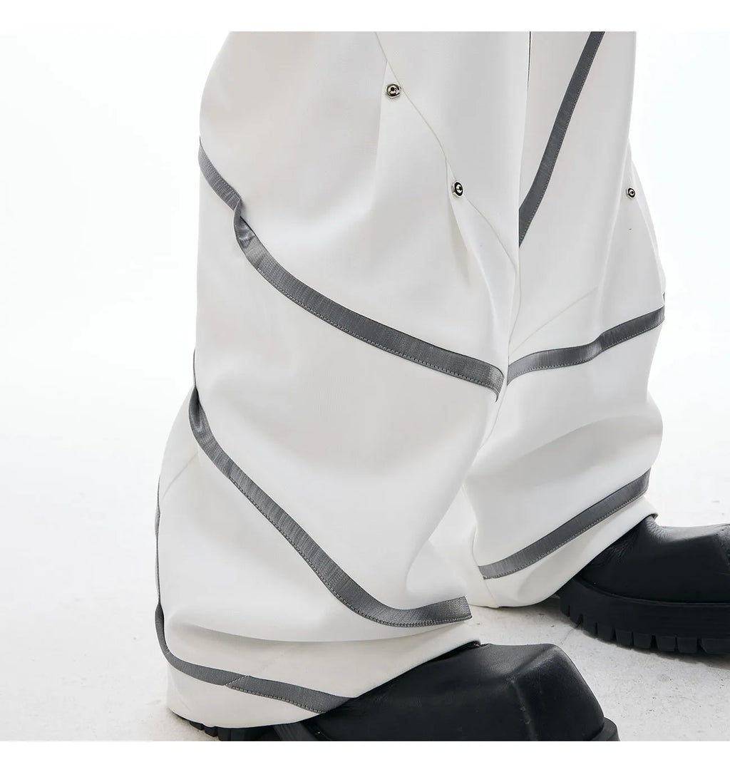 Men's black polyester trousers with front pleats and metal striped rivet details.