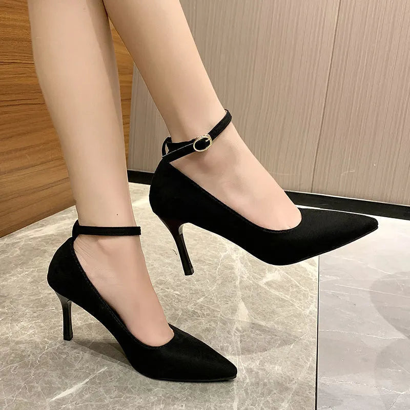 Women's black stiletto pump with ankle buckle detail and a rubber sole.