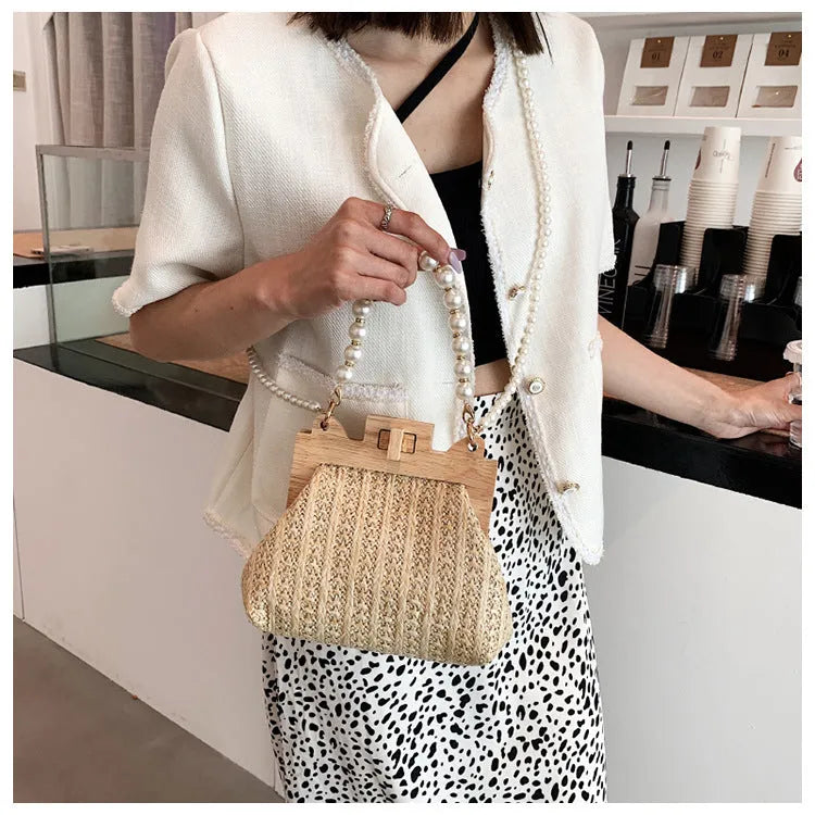 Women's straw woven shoulder bag with pearl chain detail showing internal organisation compartments