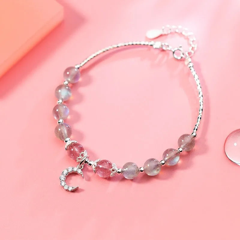 Simple handmade bracelet with round moonstone beads, a small crescent moon charm, and an adjustable metal clasp.