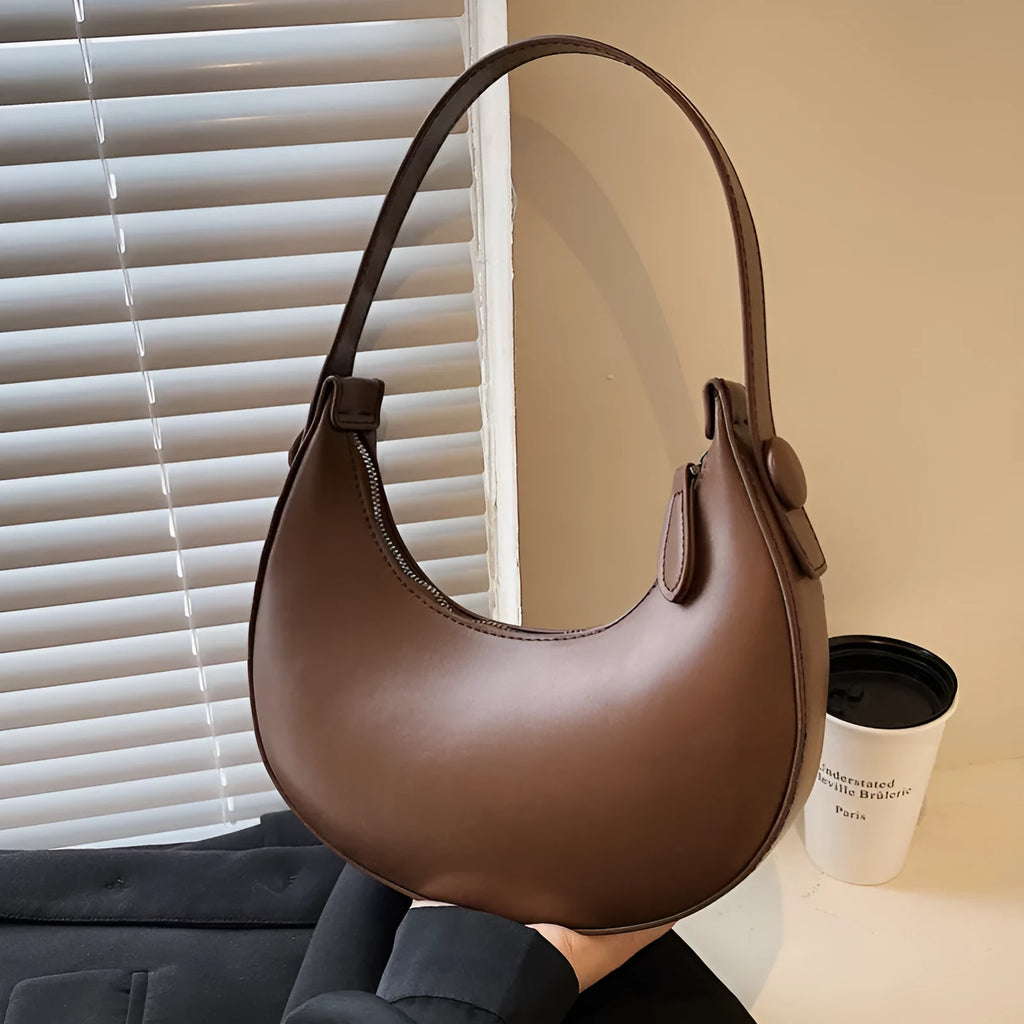 Women's retro brown dumpling-shaped PU shoulder bag showing front pocket and crossbody strap.