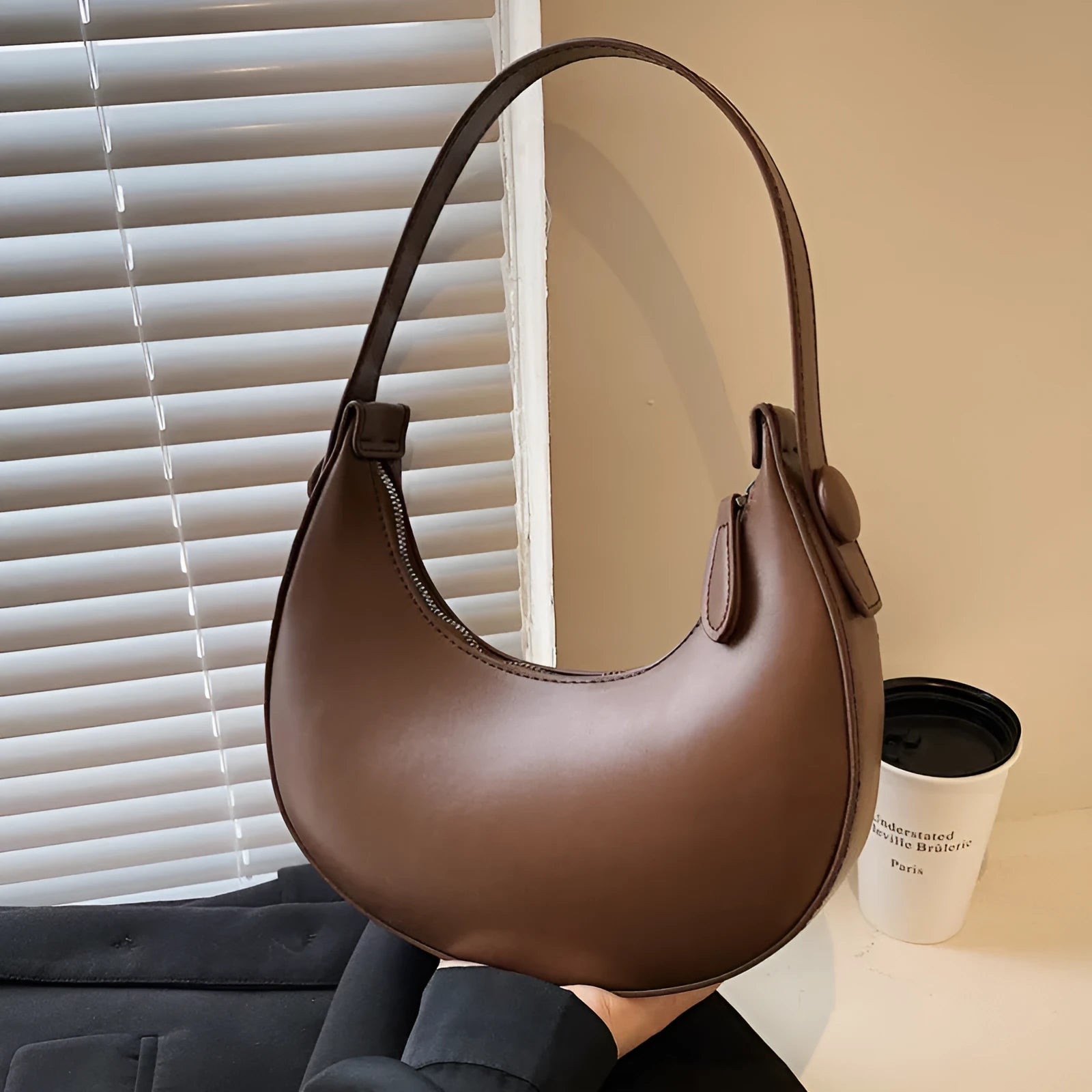 Women's retro brown dumpling-shaped PU shoulder bag showing front pocket and crossbody strap.